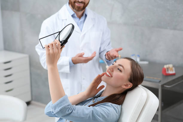 Young woman looking at her new dental implants in mirror indoors